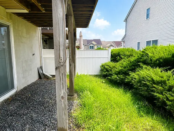 Fenced side yard beneath the deck with evergreen hedge and privacy fence
